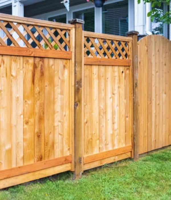 Nice wooden fence around house. Wooden fence with green lawn. Street photo, nobody, selective focus